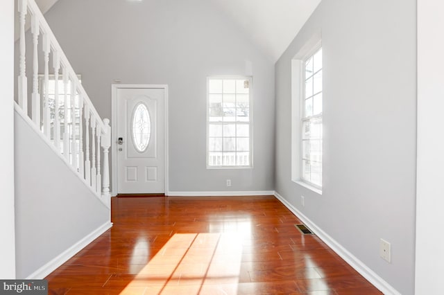 foyer entrance featuring a wealth of natural light, lofted ceiling, and wood-type flooring