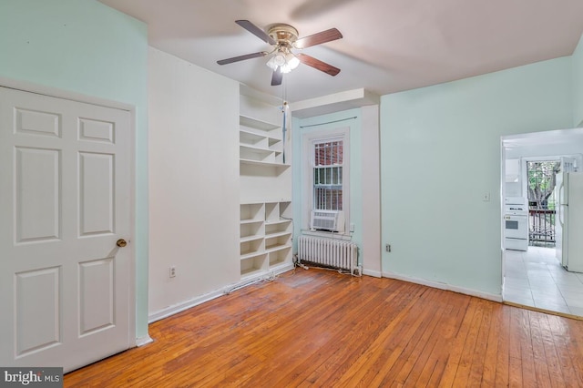 unfurnished room featuring radiator heating unit, hardwood / wood-style flooring, baseboards, and ceiling fan
