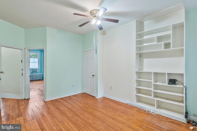 unfurnished bedroom with wood-type flooring, baseboards, and radiator