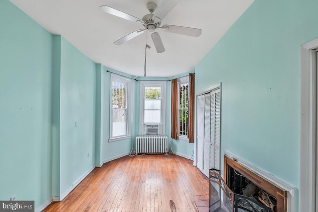 spare room featuring cooling unit, radiator, light wood-type flooring, and ceiling fan