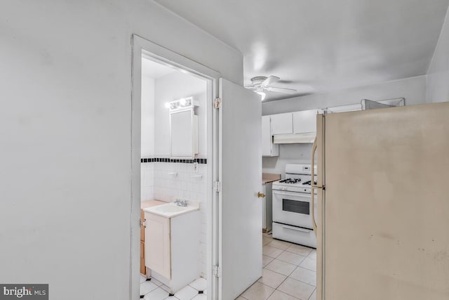 kitchen featuring ceiling fan, light tile patterned floors, white cabinetry, sink, and white appliances