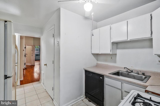 kitchen featuring white cabinets, light tile patterned floors, a sink, freestanding refrigerator, and black dishwasher