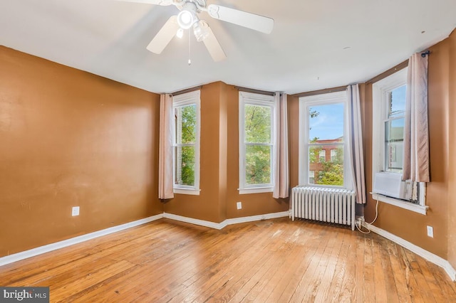 unfurnished room featuring wood-type flooring, radiator heating unit, baseboards, and ceiling fan
