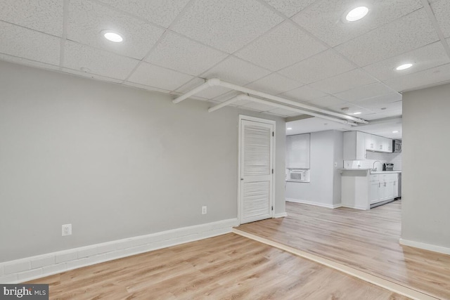 unfurnished living room featuring a drop ceiling and light hardwood / wood-style flooring