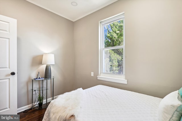 bedroom with ornamental molding and dark hardwood / wood-style floors