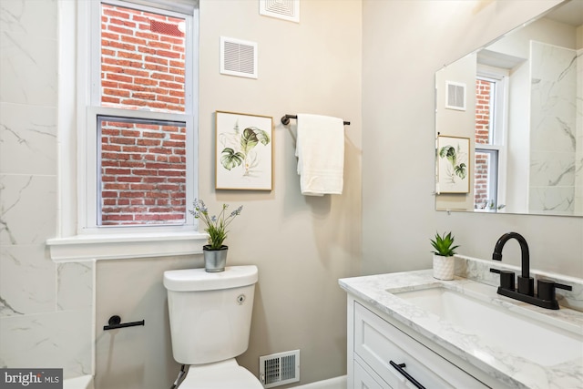 bathroom with vanity, toilet, and a healthy amount of sunlight