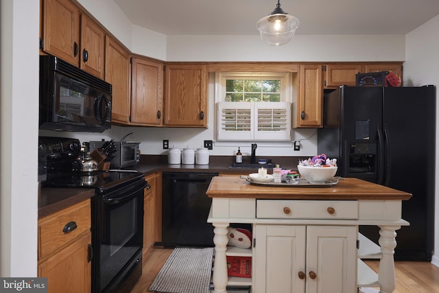 kitchen featuring pendant lighting, black appliances, wood counters, sink, and light hardwood / wood-style flooring