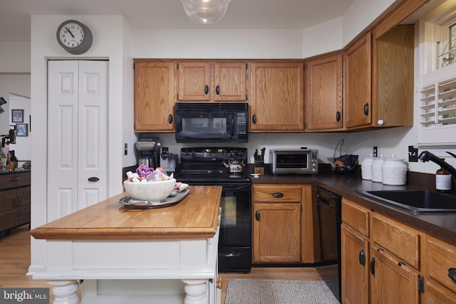 kitchen with light hardwood / wood-style floors, sink, and black appliances