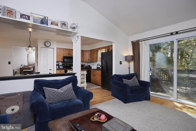 living room with high vaulted ceiling and light wood-type flooring