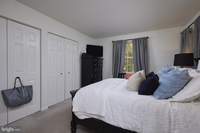 bedroom featuring light colored carpet and two closets