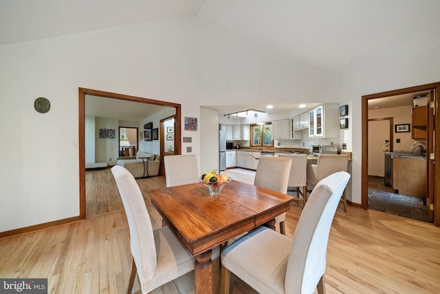 dining room featuring high vaulted ceiling and light wood-type flooring