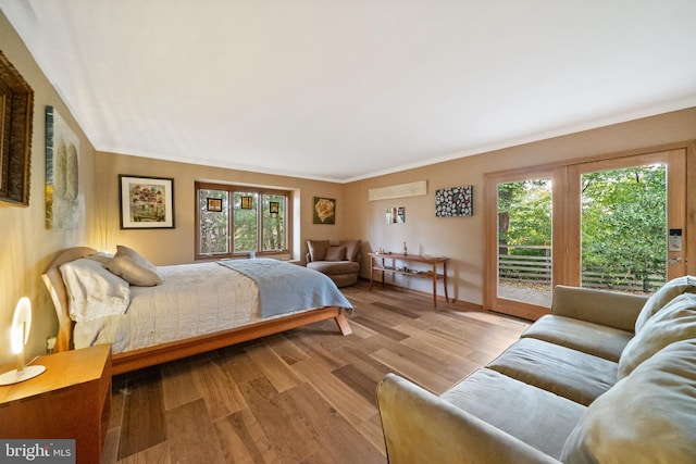 bedroom with ornamental molding, multiple windows, access to exterior, and light hardwood / wood-style floors