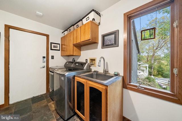 clothes washing area with sink, a healthy amount of sunlight, washing machine and dryer, and cabinets