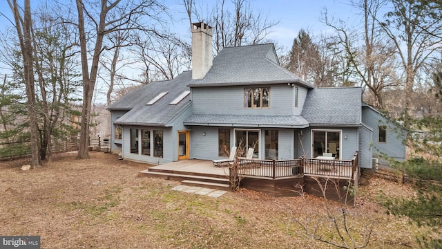 rear view of property with roof with shingles, a chimney, and a wooden deck