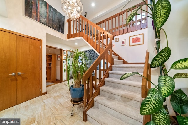 staircase with a chandelier and a high ceiling