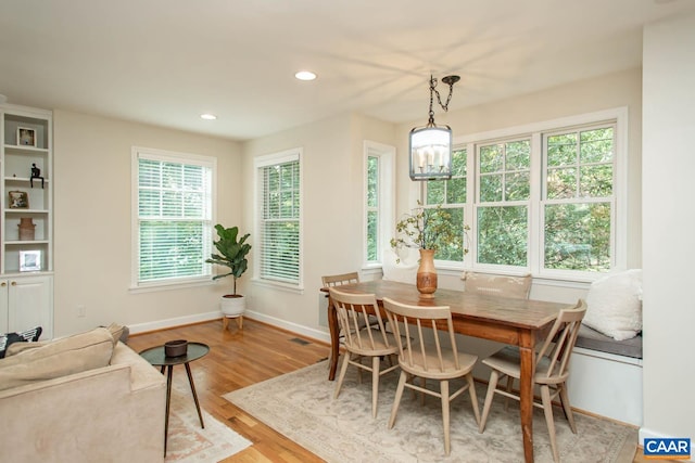 dining room with light hardwood / wood-style flooring, a notable chandelier, and plenty of natural light