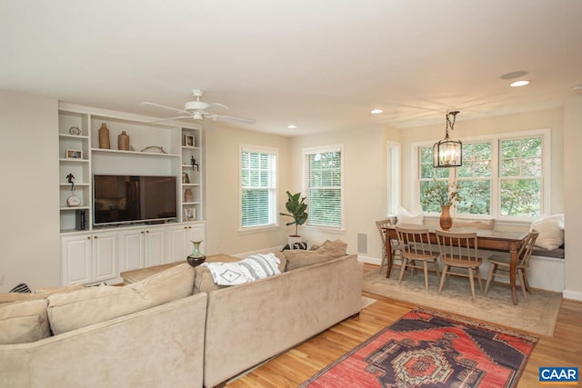 living room featuring light hardwood / wood-style flooring and ceiling fan with notable chandelier