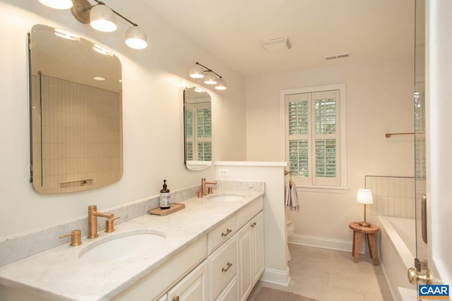 bathroom featuring vanity, toilet, a relaxing tiled tub, and tile patterned flooring