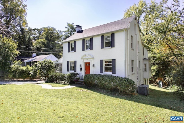 colonial-style house featuring a front lawn and central AC unit