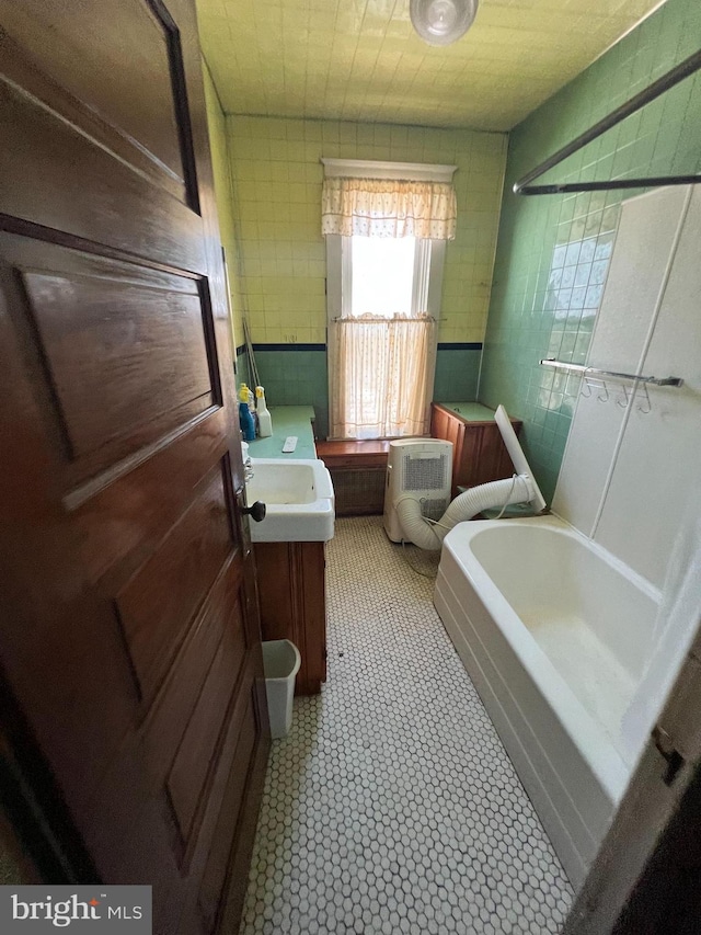 bathroom with toilet, a bathtub, vanity, and tile walls