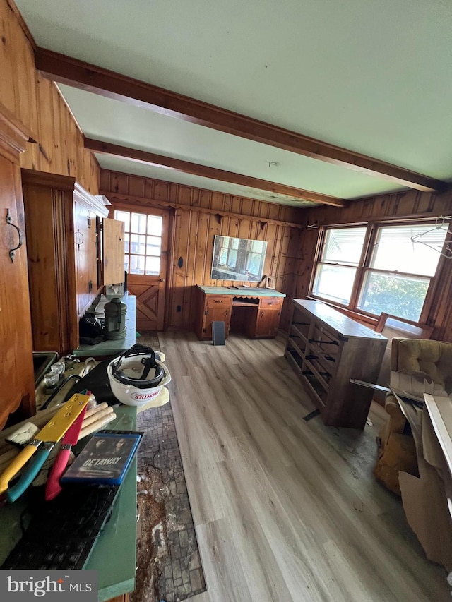 interior space featuring wooden walls, beamed ceiling, and plenty of natural light