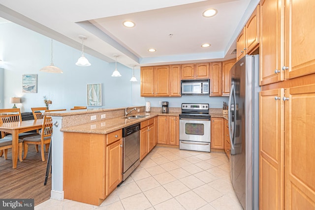 kitchen with light stone countertops, sink, kitchen peninsula, stainless steel appliances, and decorative light fixtures