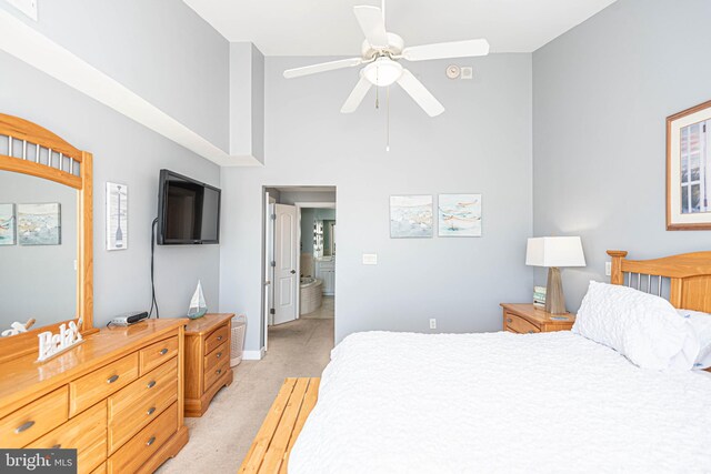 bedroom with ensuite bathroom, light colored carpet, a towering ceiling, and ceiling fan