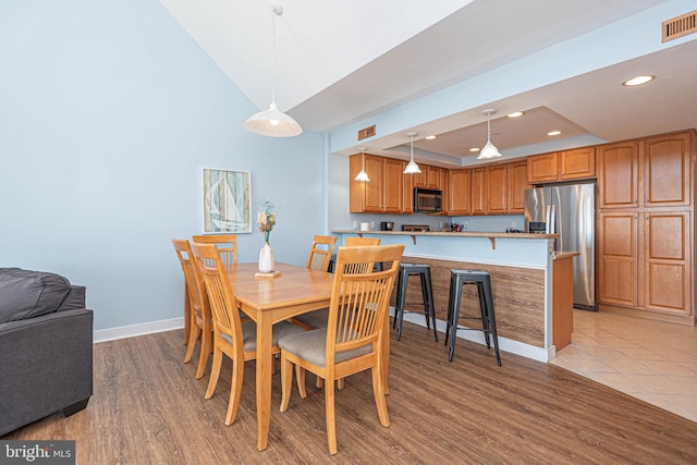 dining space featuring a tray ceiling and light wood-type flooring