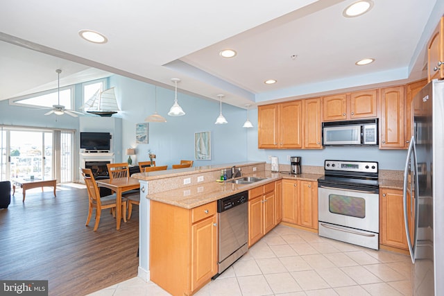 kitchen with kitchen peninsula, hanging light fixtures, ceiling fan, appliances with stainless steel finishes, and sink