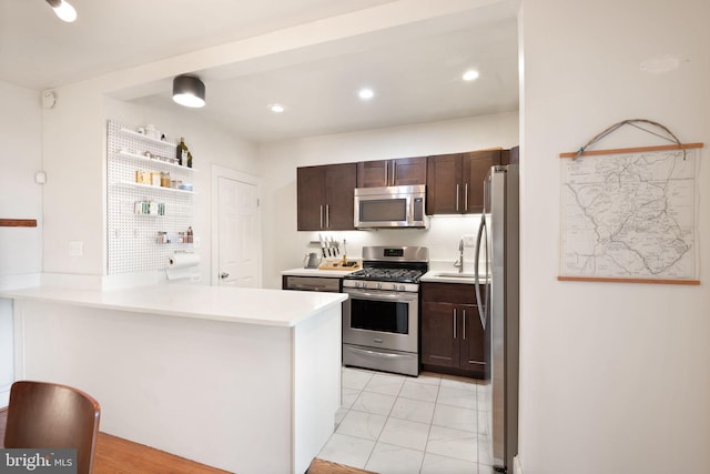 kitchen featuring kitchen peninsula, dark brown cabinetry, stainless steel appliances, and sink