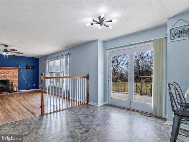 unfurnished living room featuring a brick fireplace, a notable chandelier, and a textured ceiling