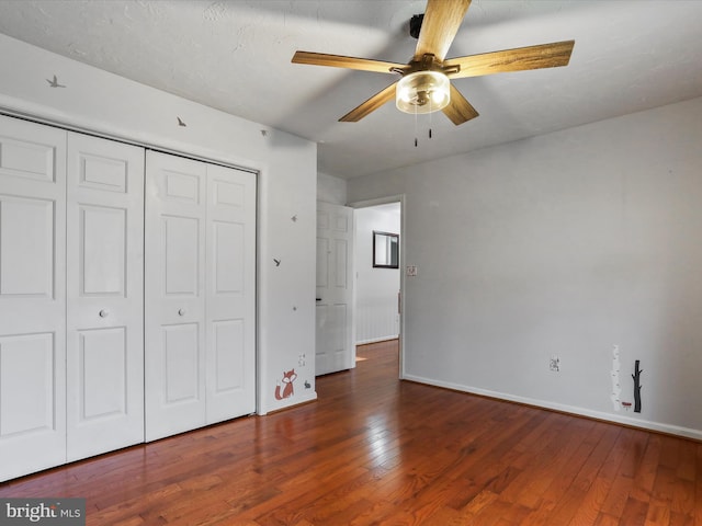 unfurnished bedroom with dark wood-type flooring, ceiling fan, and a closet