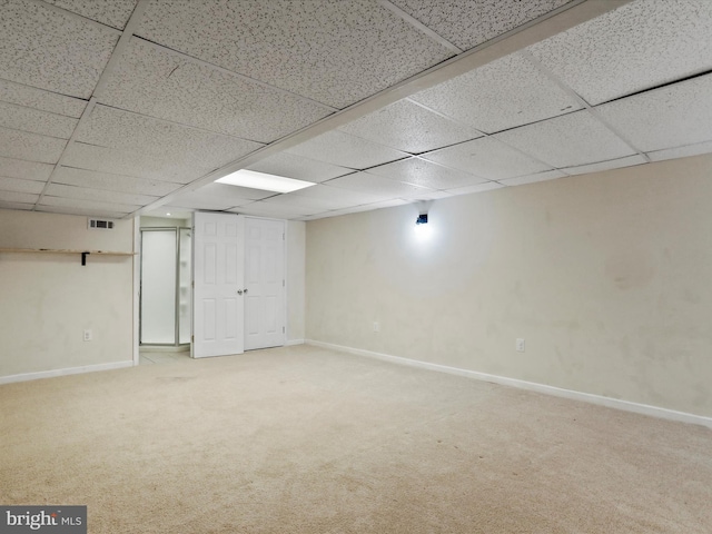 basement featuring a paneled ceiling and carpet flooring