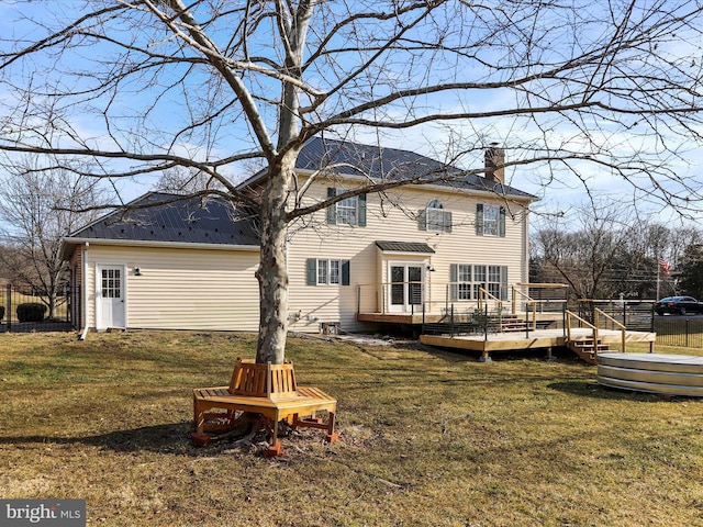 back of property featuring a wooden deck and a lawn