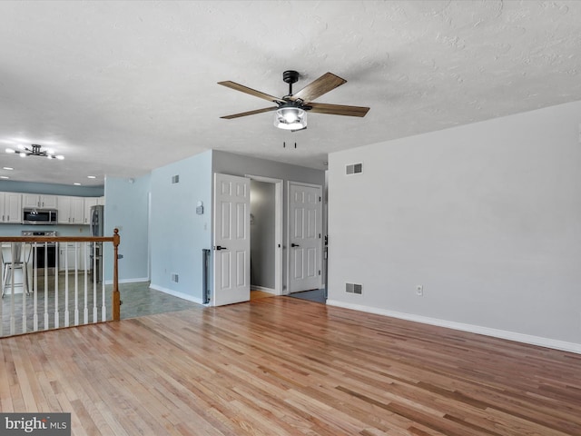 spare room featuring ceiling fan, a textured ceiling, and light hardwood / wood-style floors