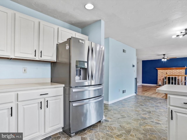 kitchen featuring a brick fireplace, ceiling fan, white cabinets, and stainless steel refrigerator with ice dispenser