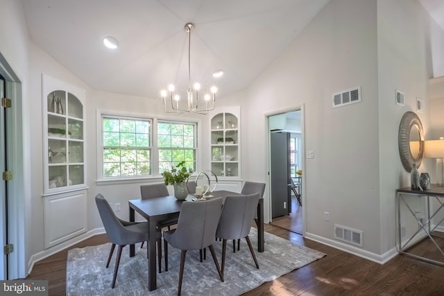 dining area featuring lofted ceiling, dark hardwood / wood-style flooring, and an inviting chandelier