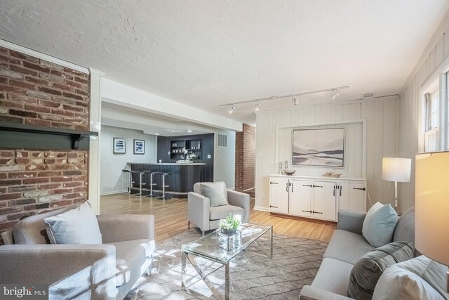 living room with rail lighting, a textured ceiling, and light wood-type flooring