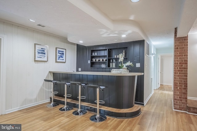 bar featuring light hardwood / wood-style flooring, a textured ceiling, and wood walls