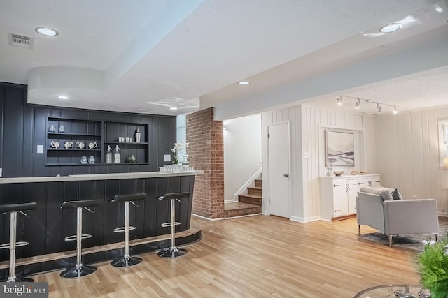 bar featuring white cabinets, a textured ceiling, and light wood-type flooring