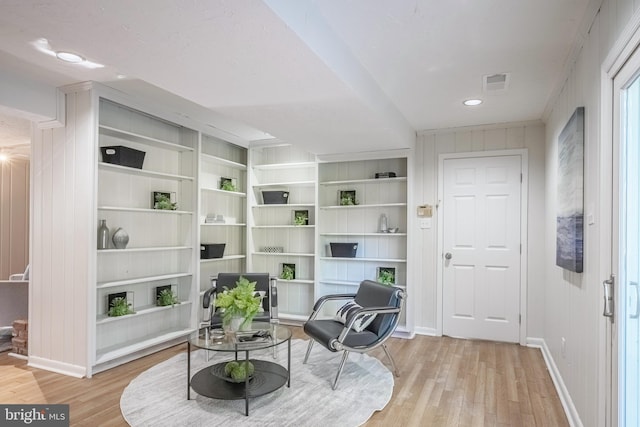 living area featuring light wood-type flooring and wood walls