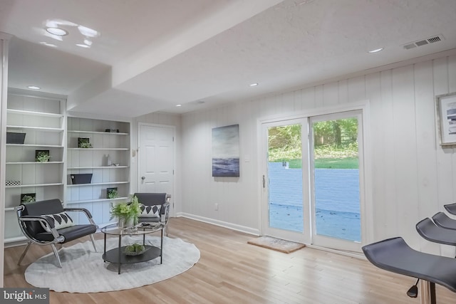 living area featuring light hardwood / wood-style floors and wooden walls