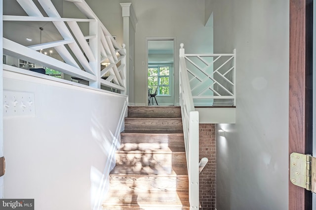 stairway with beam ceiling, wood-type flooring, and high vaulted ceiling