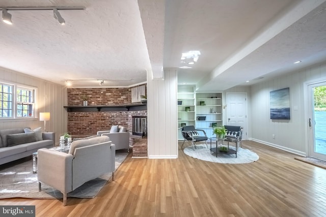 living room featuring a wealth of natural light, track lighting, a textured ceiling, and light wood-type flooring