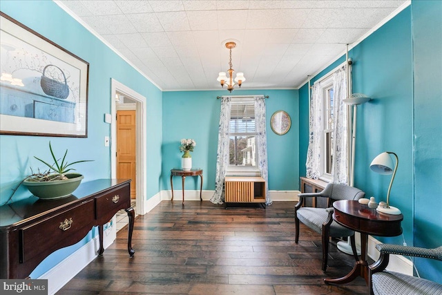 living area featuring ornamental molding, dark wood-type flooring, and a chandelier