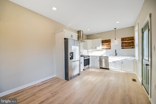 kitchen featuring appliances with stainless steel finishes, hanging light fixtures, white cabinets, and light hardwood / wood-style floors