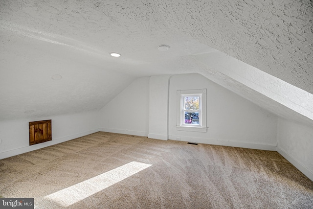 bonus room featuring vaulted ceiling, a textured ceiling, and carpet flooring