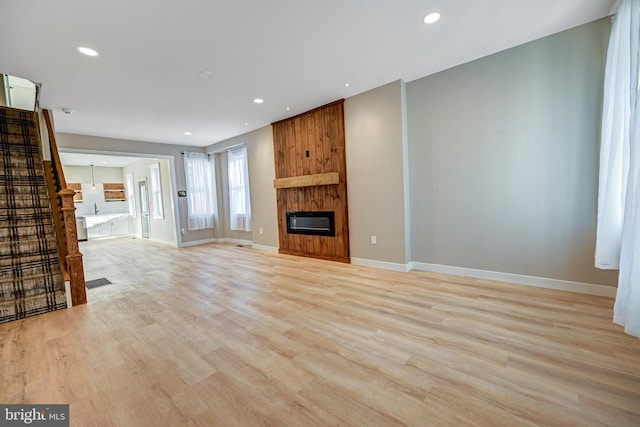 unfurnished living room featuring light hardwood / wood-style flooring, heating unit, and a fireplace