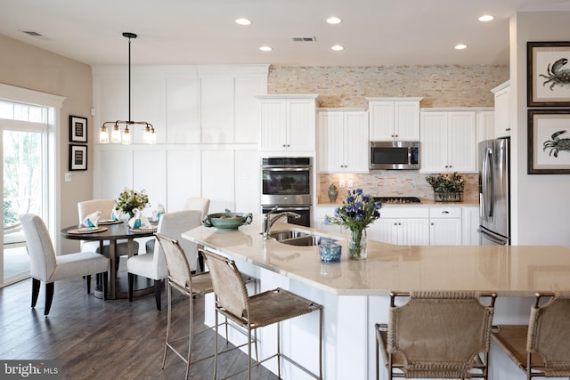 kitchen featuring appliances with stainless steel finishes, white cabinetry, dark hardwood / wood-style floors, and pendant lighting