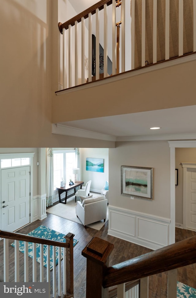 stairway with a towering ceiling, crown molding, and hardwood / wood-style floors